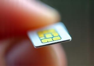 Hand holding a small SIM card chip